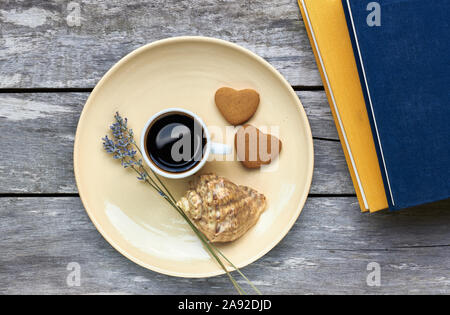 Petit-déjeuner scandinave à la mer : café, biscuits en forme de coeur, lavande, Shell et des livres sur la vieille table en bois patiné, profiter de moments simples de votre Banque D'Images