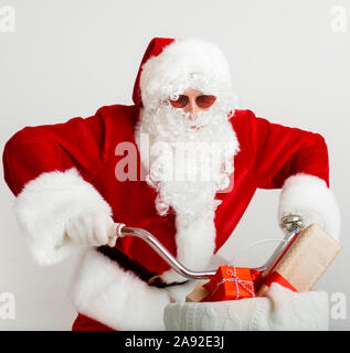 Père Noël en lunettes de soleil et d'une bicyclette avec des cadeaux Banque D'Images