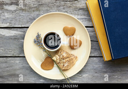 Petit-déjeuner scandinave à la mer : café, biscuits en forme de coeur, lavande, Shell et des livres sur la vieille table en bois patiné, profiter de moments simples de votre Banque D'Images