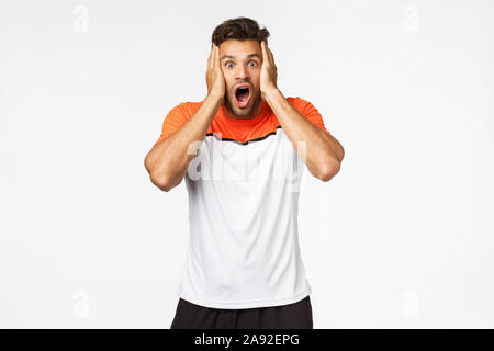 Choqué, sans voix beau mascular athlète masculin de sports t-shirt, haletant, drop jaw préoccupé et stupéfait, prenez votre visage de stupéfaction, d'entendre Banque D'Images