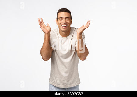 Heureux surpris beau homme brésilien avec des gros muscles, ouvrir les yeux et sourire amusé, recevoir des cadeaux fantastiques pour Noël, debout étonné Banque D'Images