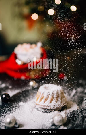 Noël au chaud à la maison avec un sweet mini gâteau bundt, le sucre en poudre sur une mini hot chaud Gâteau bundt avec ornement de Noël et une tasse de flou artistique Banque D'Images