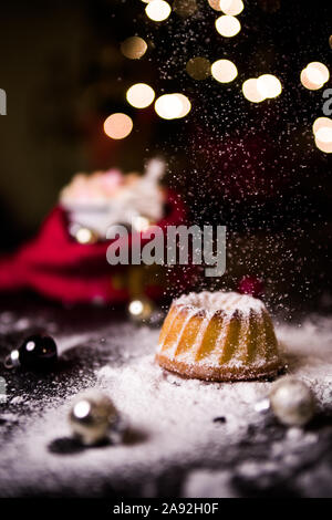 Noël au chaud à la maison avec un sweet mini gâteau bundt, le sucre en poudre sur une mini hot chaud Gâteau bundt avec ornement de Noël et une tasse de flou artistique Banque D'Images