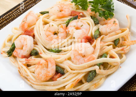 Langoustines Crevettes faite avec linguini, asperges, tomates en dés, le beurre, l'ail, les herbes et le persil. Servi sur des plaques carrées superposées. Tourné en lumière naturelle Banque D'Images