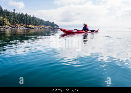 Une femme du kayak de mer dans la matinée au large de l'île Orcas dans Rosario Strait, Washington, USA. Banque D'Images