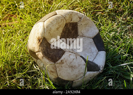 Déchiré au football sur la pelouse. Ballon de soccer peau déchirée sur le terrain, mais encore utilisés pour jouer. Banque D'Images