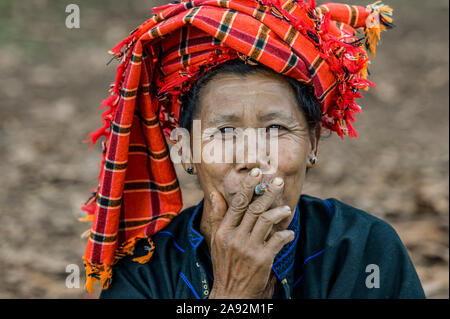 Femme birmane portant une couverture traditionnelle de la tête et fumant une cigarette; Yawngshwe, État Shan, Myanmar Banque D'Images