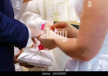 Bride d'or met sur un anneau de mariage pour le marié Banque D'Images