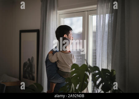 Père avec bébé à la recherche d'une fenêtre Banque D'Images