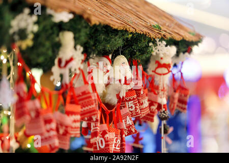 Décorations de Noël sur l'étal du marché avec des petits sacs comme calendrier de l'Avent avec bonbons surprises suspendu à un ruban à l'arrière-plan flou lumières Banque D'Images