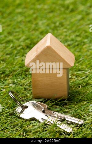 Modèle de maison miniature en bois peu sur fond d'herbe verte avec des clés de la maison écologique - vivant ou la construction de concept, selective focus Banque D'Images