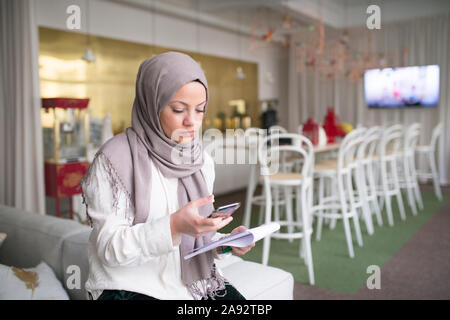 Young woman with smartphone in office Banque D'Images