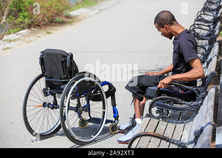 Homme qui avait une méningite spinale avec un fauteuil roulant se relaxant un parc Banque D'Images