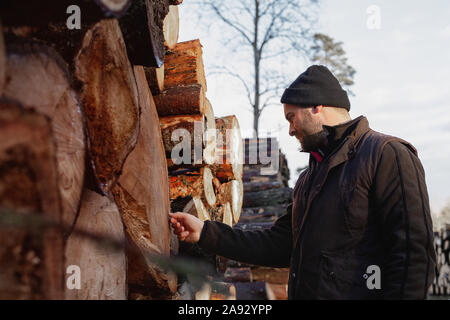 Homme debout en face de pile de grumes Banque D'Images