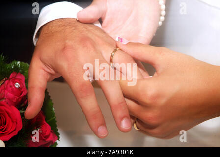 La main de la mariée met l'anneau de mariage au doigt du marié Banque D'Images