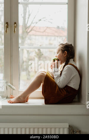 Girl sitting on windowsill Banque D'Images