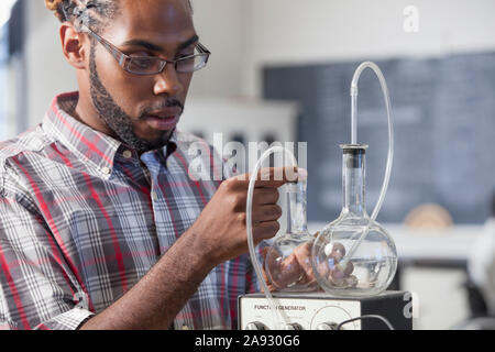 Étudiant qui a eu la méningite spinale installer des flacons pour un expérience de volume par rapport à la pression en laboratoire Banque D'Images