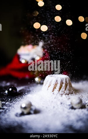 Noël au chaud à la maison avec un sweet mini gâteau bundt, le sucre en poudre sur une mini hot chaud Gâteau bundt avec ornement de Noël et une tasse de flou artistique Banque D'Images