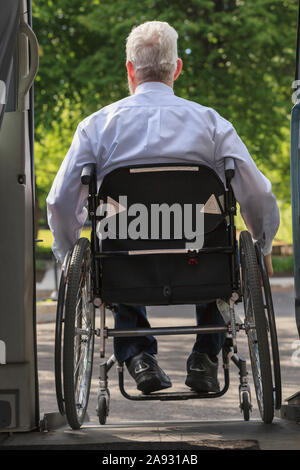 Homme d'affaires avec dystrophie musculaire dans un fauteuil roulant sortant de son accessible minibus dans le parking Banque D'Images