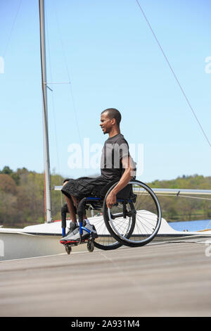 Homme en fauteuil roulant qui avait une méningite spinale à un quai à voile Banque D'Images