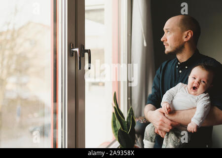 Père avec bébé à la recherche d'une fenêtre Banque D'Images