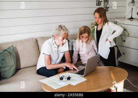 Grand-mère avec petites-filles using laptop Banque D'Images