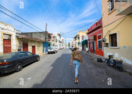 SANTO DOMINGO, RÉPUBLIQUE DOMINICAINE - le 26 juin 2019 : femme marchant le long d'une rue. Vue d'Amérique du Sud - paysage urbain typique avec des voitures de rue, motorcyc Banque D'Images
