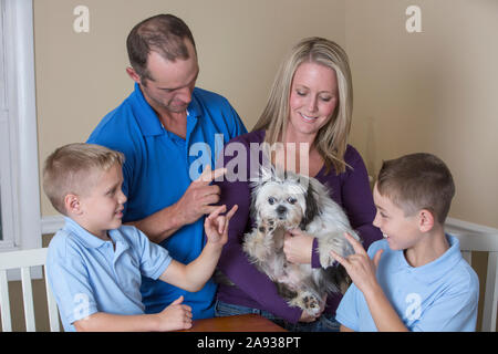 Famille avec des troubles de l'audition assis autour d'une table décrivant « l'amour Et New Puppy en American Sign Language Banque D'Images