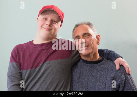 Portrait du jeune homme heureux avec le syndrome de Down et son Père avec lésion de la moelle épinière à la maison Banque D'Images