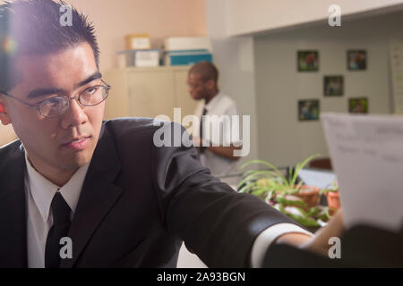 Homme asiatique avec autisme travaillant dans un bureau pour atteindre un papier Banque D'Images