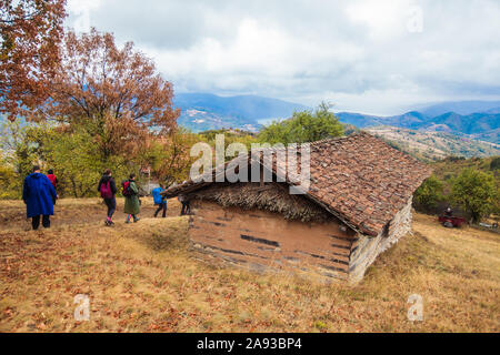 Groupe de gens actifs randonnées sur la journée d'automne pluvieuse vêtu d'un imperméable. Du vrai méconnaissable randonneurs, rétroviseurs, ciel nuageux dans l'arrière-plan. Banque D'Images