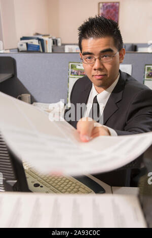 Homme asiatique avec autisme faisant de la paperasse dans un bureau Banque D'Images