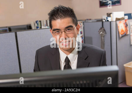 Portrait d'un homme asiatique heureux avec l'autisme travaillant sur ordinateur dans un bureau Banque D'Images