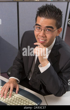 Homme asiatique heureux avec l'autisme travaillant sur l'ordinateur dans un bureau Banque D'Images