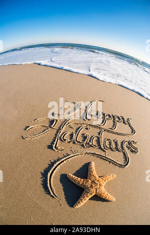 Bonnes vacances message écrit dans le sable lisse avec effet fisheye sur mer et vagues blanc mousseux Banque D'Images