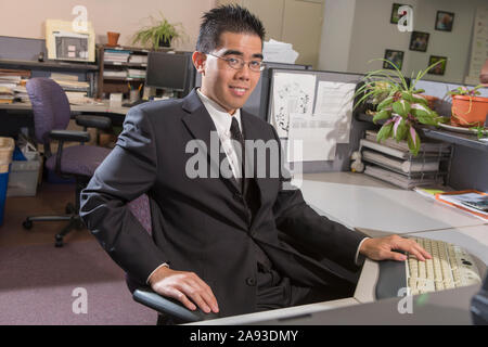 Portrait d'un homme asiatique heureux avec l'autisme travaillant sur ordinateur dans un bureau Banque D'Images