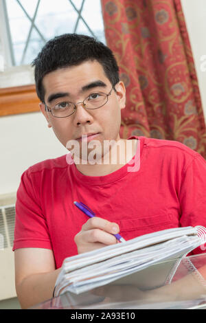 Portrait de l'homme asiatique avec l'autisme travaillant sur ses devoirs Banque D'Images