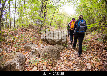 Groupe de gens actifs randonnées sur la journée d'automne pluvieuse vêtu d'un imperméable. Du vrai méconnaissable randonneurs, rétroviseurs, ciel nuageux dans l'arrière-plan. Banque D'Images
