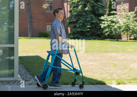 Jeune homme avec paralysie cérébrale utilisant son marcheur pour marcher au travail Banque D'Images
