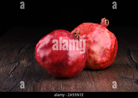 Deux grenades mûres sur une table en bois et un arrière-plan sombre.. Style rustique. Copier l'espace. Banque D'Images