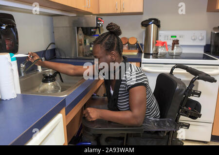 Adolescent avec paralysie cérébrale travaillant dans la cuisine Banque D'Images