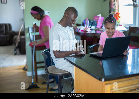 Famille travaillant sur ordinateur, homme avec le syndrome de Williams Banque D'Images