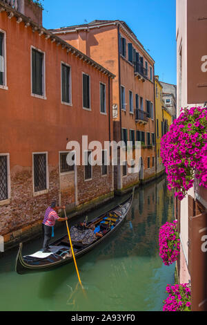 Venise, Italie - 20 juillet 2019 : un couple bénéficiant d'une promenade romantique en gondole dans les ruelles d'canalways la ville historique de Venise en Italie. Banque D'Images