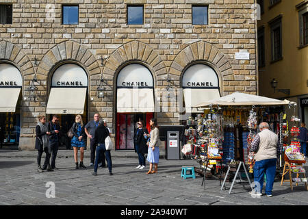 Blocage de souvenirs avec vendeur de rue en face de la boutique Chanel mode en place Signoria dans le centre historique de Florence, Toscane, Italie Banque D'Images