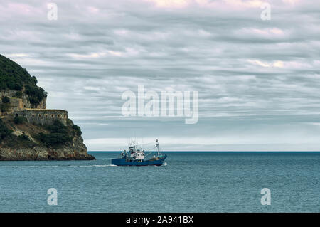 Bleu bateau quitter l'estuaire de la rivière Ason d'aller à la pêche dans le golfe de Gascogne à Laredo, Cantabrie, Espagne. Banque D'Images