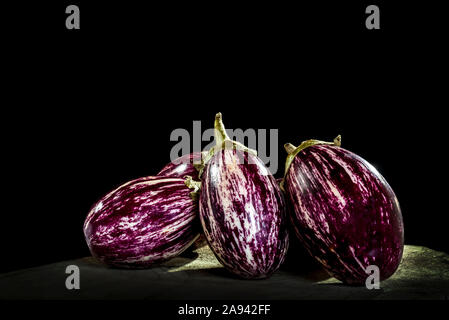 Aubergine à rayures violettes et blanches sur un panneau en bois avec un arrière-plan noir Banque D'Images