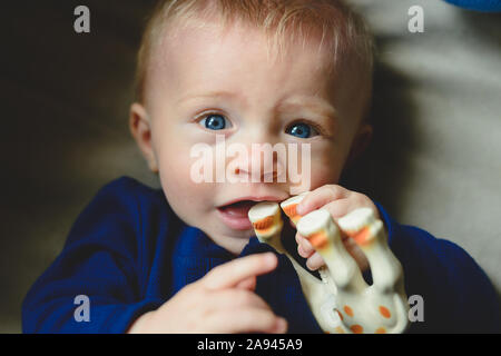 Un petit garçon mâchonne un jouet. Banque D'Images