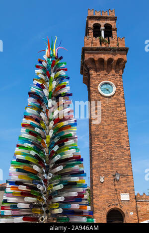 Murano, Italie - 19 juillet 2019 : un arbre fabriqué à partir de verre de Murano avec le clocher médiéval de l'église San Stefano dans le bcakground, sur l'est de Venise Banque D'Images