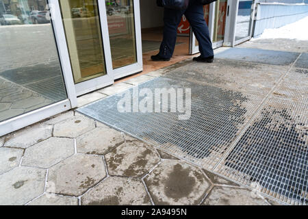 Yekaterinburg, Russie - Novembre 2019. Portes en verre automatique ouvrir et fermer. Entrée du centre commercial. L'hiver. Des empreintes humides sur le sol. Les jambes de Banque D'Images