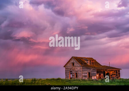 Grange abandonnée sur une terre agricole avec des nuages orageux rose éclatant; Val Marie, Saskatchewan, Canada Banque D'Images